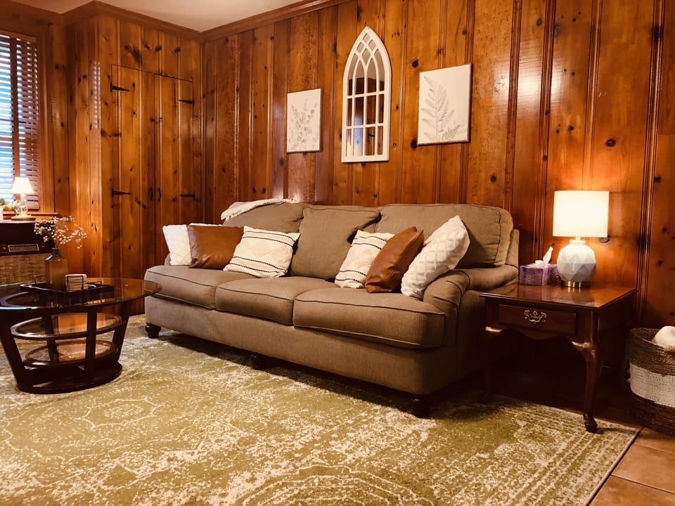 Comfy 3-seat sofa with warm, honey pine wood panel walls.