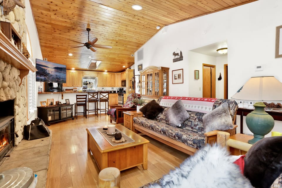 Cozy mountain living room with a stone fireplace, comfy seating, and smart TV—perfect for relaxing evenings, movie nights, and warm cabin vibes after outdoor adventures.