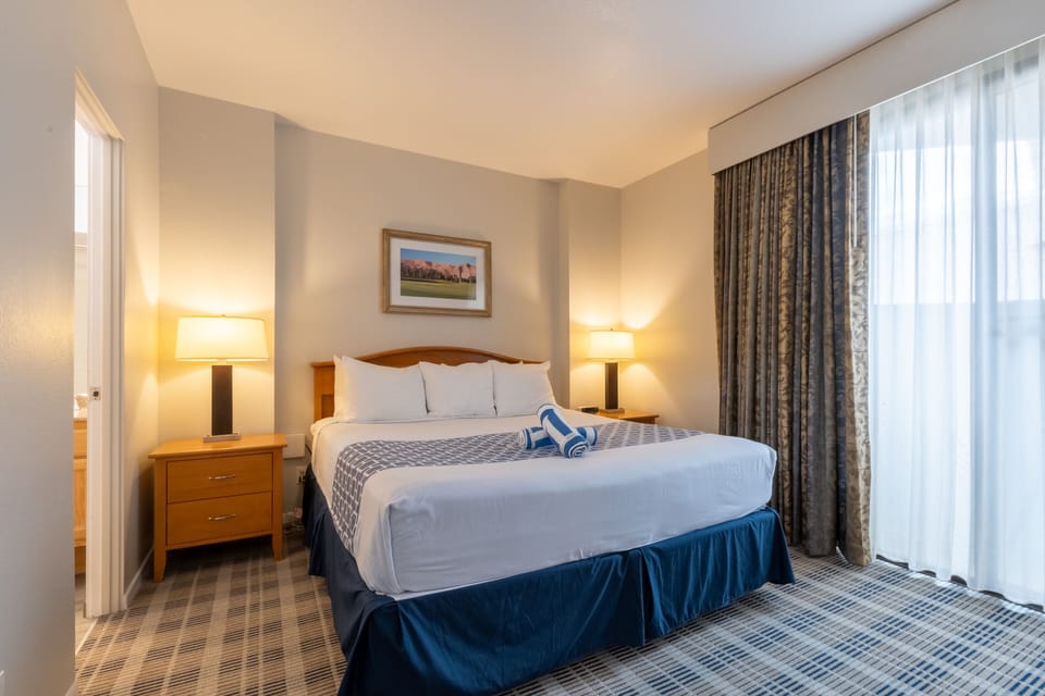 Unwind in a plush king bed with soft lamplight.