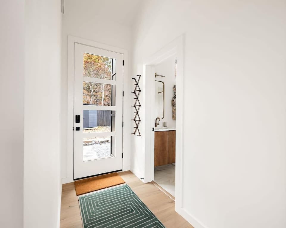 First impressions matter and this entryway delivers. A modern door with glass panels lets natural light pour in, welcoming you with warm tones, sleek hooks for your gear, and a clean, calming aesthetic from the moment you step inside.