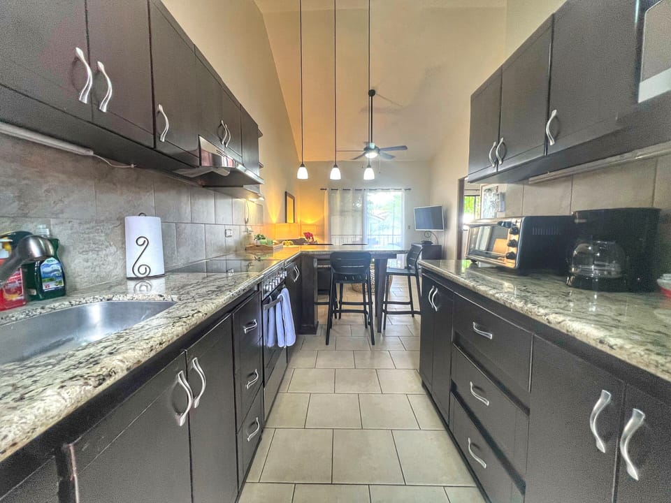 The condo has an open concept living space with the kitchen, dining and living room flowing out to the shaded patio.