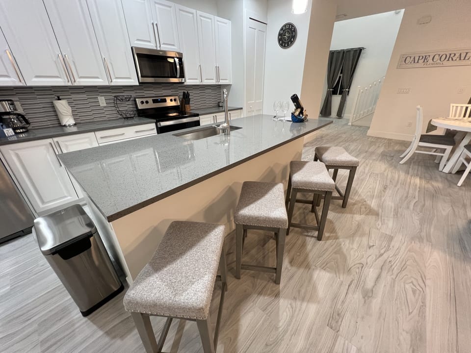 Kitchen equipped with coffee maker, dinnerware, cups, wine glasses, blender