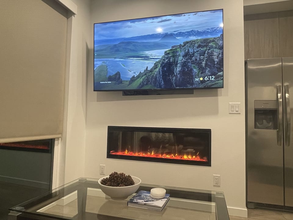 Living room has 75” moveable smart TV and an indoor fire place.