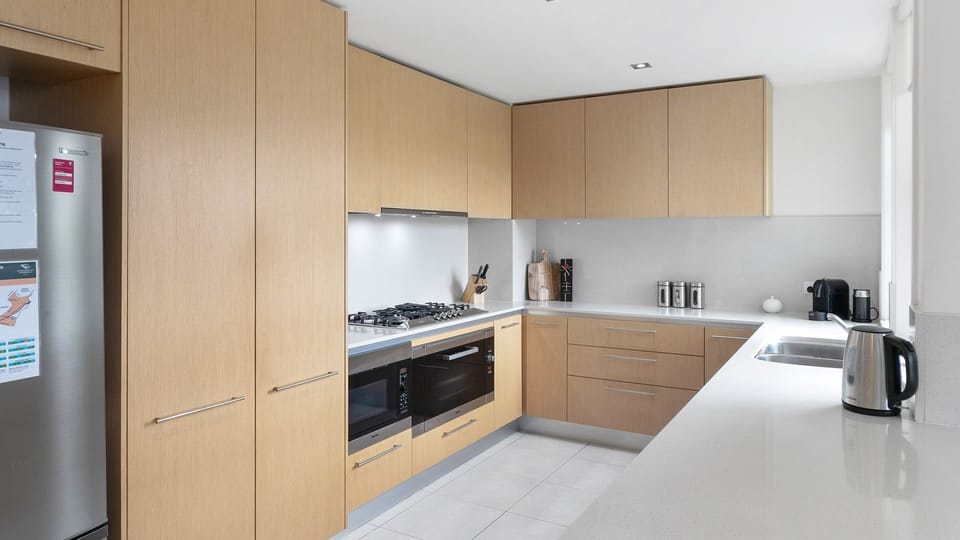 Kitchen equipped with microwave, oven, cooktop, coffee machine, rice maker and fridge freezer.