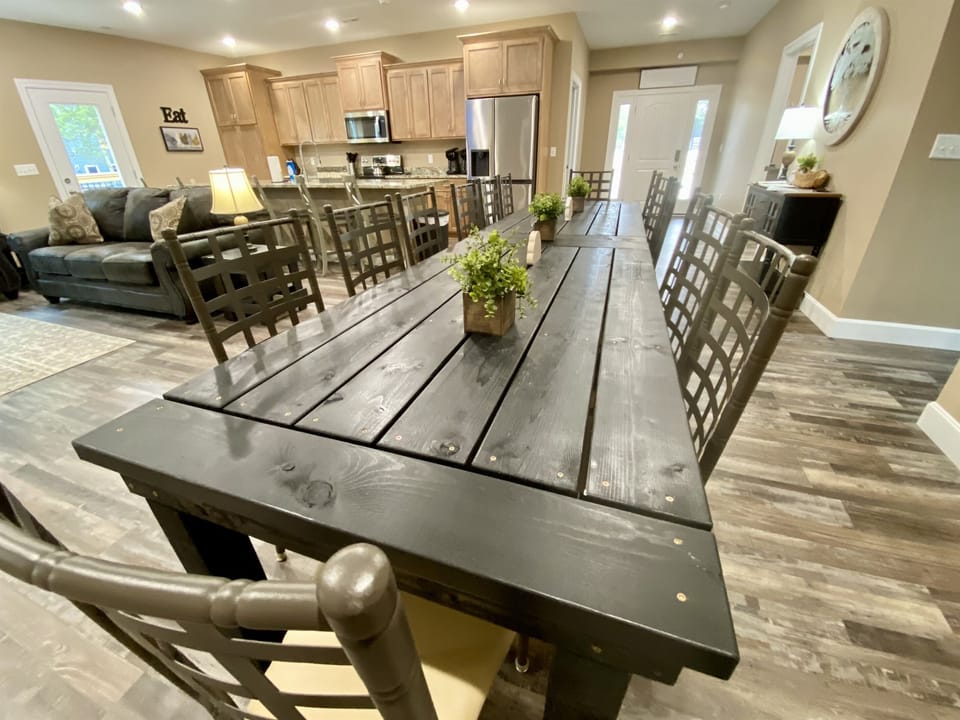Large custom build dining table seats 14 with 6 island seats on an open kitchen/dining/living space.