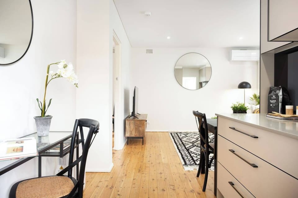 Light, polished timber floorboards, chic timber furniture and thoughtful decor decorate a naturally-lit space
