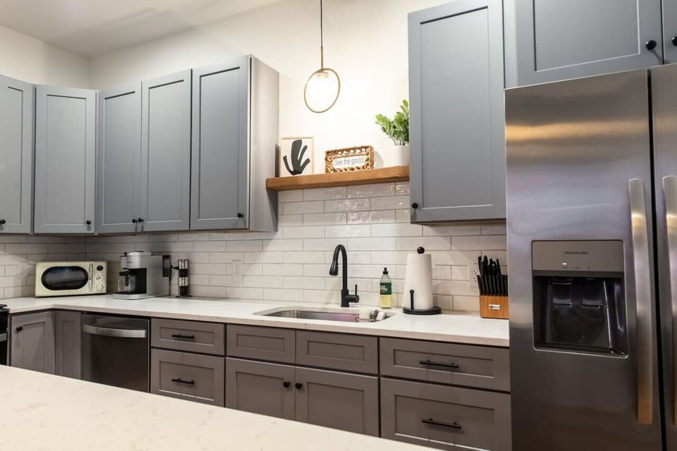 Modern kitchen with gray cabinets, a white island, stainless steel appliances and pendant lighting