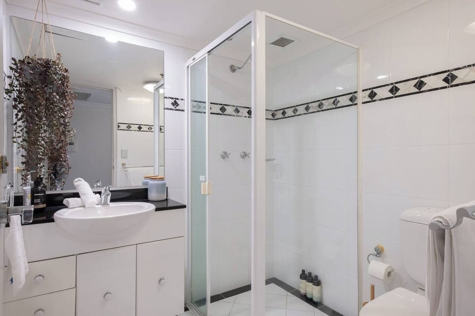 The pristine, black and white tiled bathroom offers an enclosed shower and large mirror.

