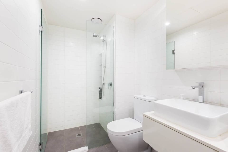 The bathroom is sleek and modern, featuring a floating vanity, toilet and adjustable showerhead.