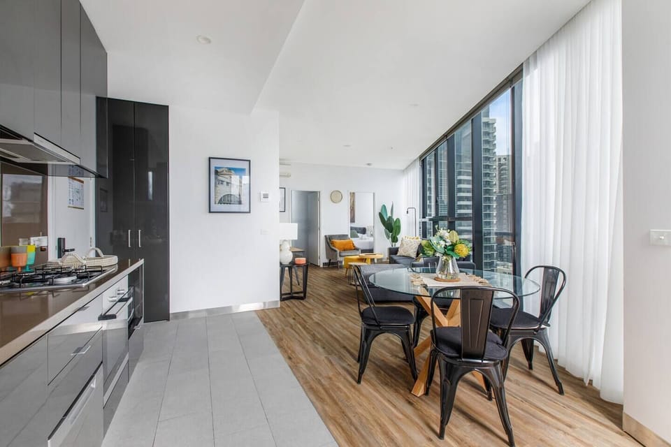 The open-plan kitchen and dining area includes a four-seater table to enjoy meals at home, with floor-to-ceiling windows offering sweeping views of the city.  
