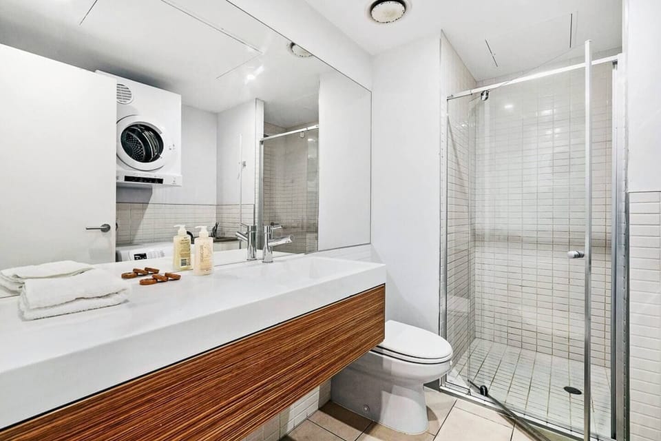 The bathroom is bright and modern with a shower, oversized vanity, toilet and in-unit laundry.