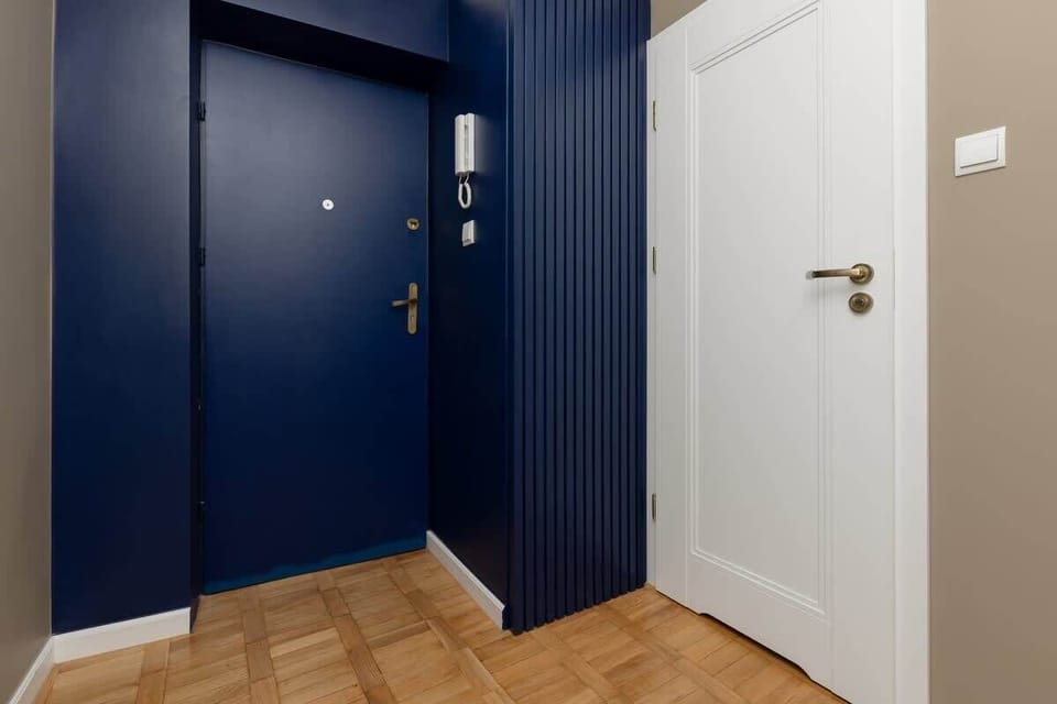 The hallway near the entrance, showcasing the front door in dark blue and a minimalistic, clean layout.