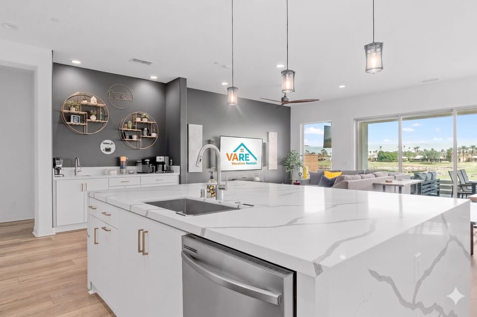 Quartz island with coffee bar—gray accent wall and round mirrors.