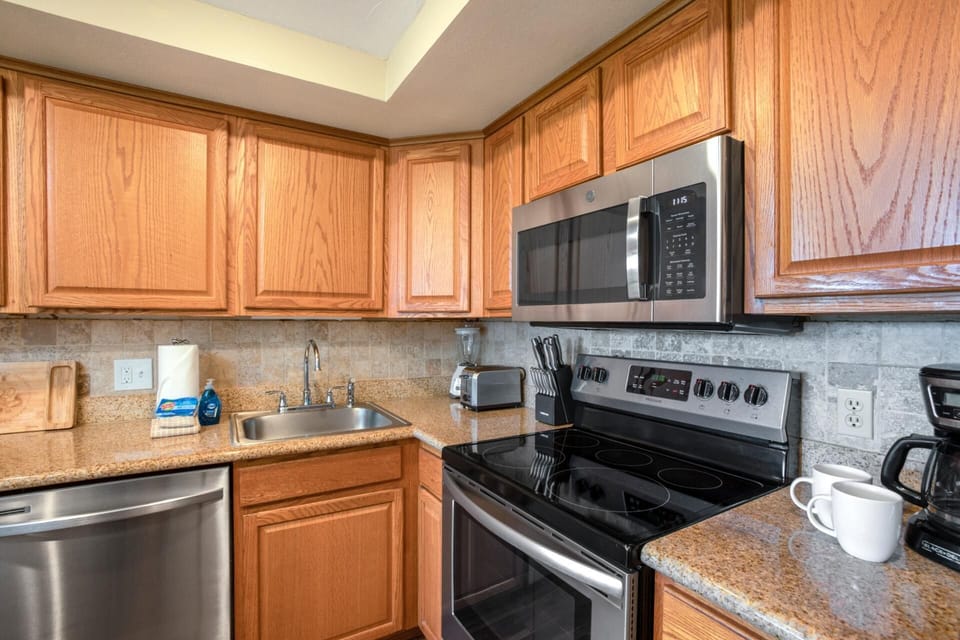 A cheerful kitchen with stainless steel appliances, soft lighting, and comfy stools perfect for casual dining   