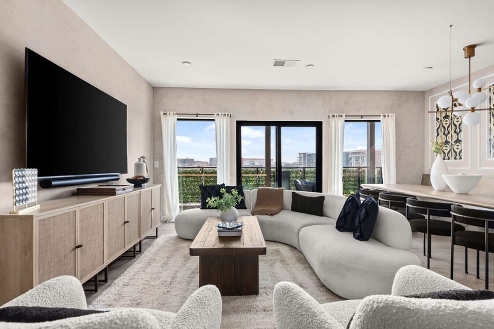 The stylish living room has a unique curved sofa, large windows, and a sophisticated ambiance, ideal for modern living.