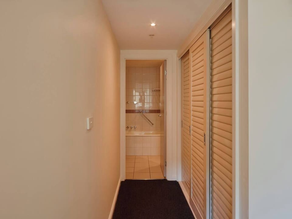 A built-in wardrobe connects the bedroom area and bathroom.