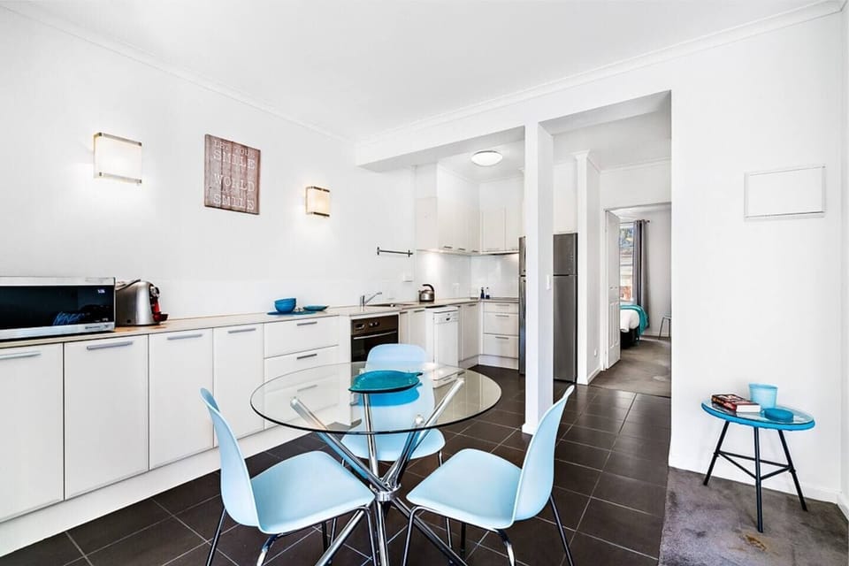 The eat-in kitchen features a sleek glass dining table and all the essentials to cook at home.