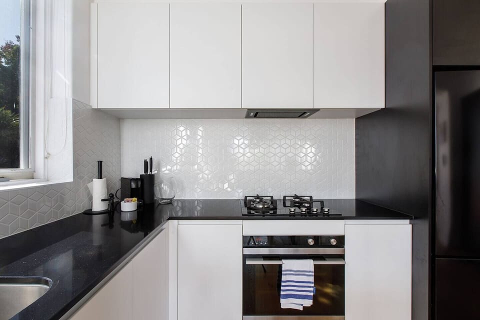 A stylish monochrome kitchen comes fully equipped for meals at home with sleek appliances and utensils.