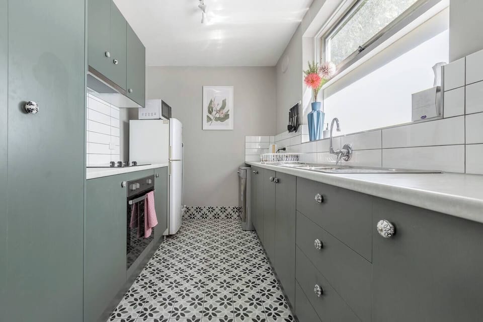 Channel your inner chef in this galley-style kitchen, equipped with premium appliances, sage cabinets, and black and white tiles to inspire your culinary adventures.