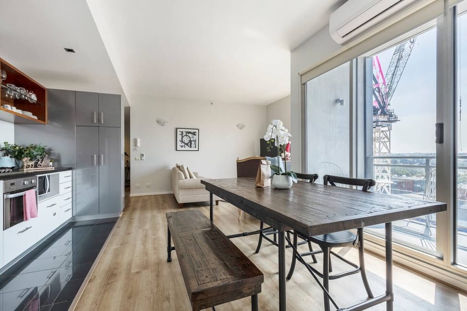 The living room floats effortlessly into a dining space featuring a stunning, dark timber table for four