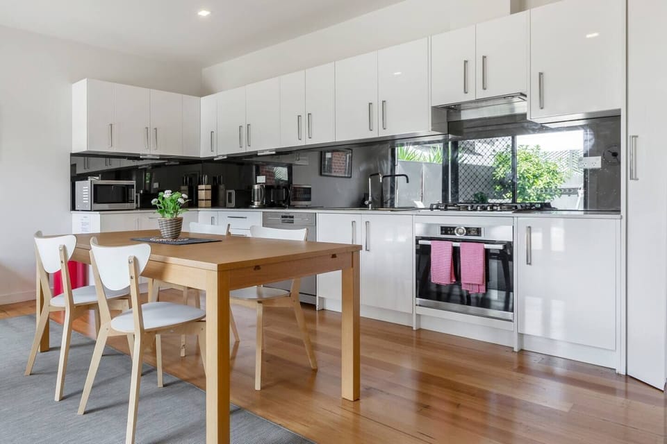 A spacious dining room has polished timber flooring and a timber dining table that can seat six people