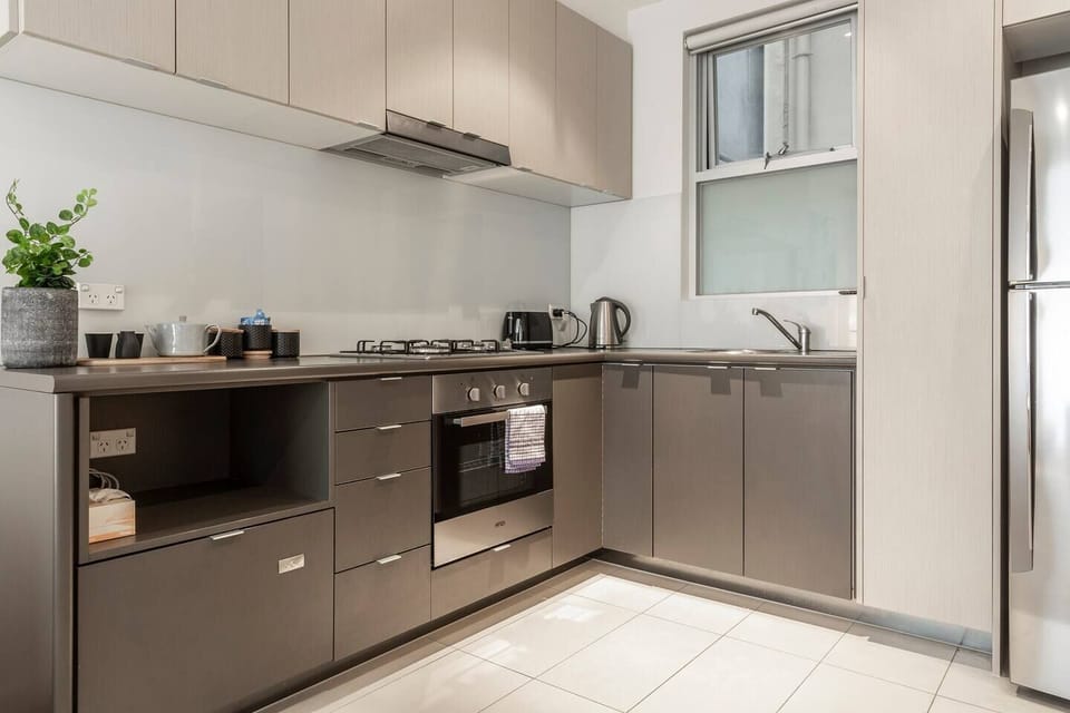 A sleek, fully-equipped kitchen features state-of-the-art appliances including a gas cooktop, oven and full-sized fridge