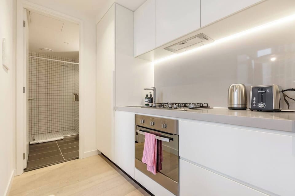 A small, fully-equipped kitchen features modern appliances like a large fridge, microwave, gas stovetop, oven and dishwasher
