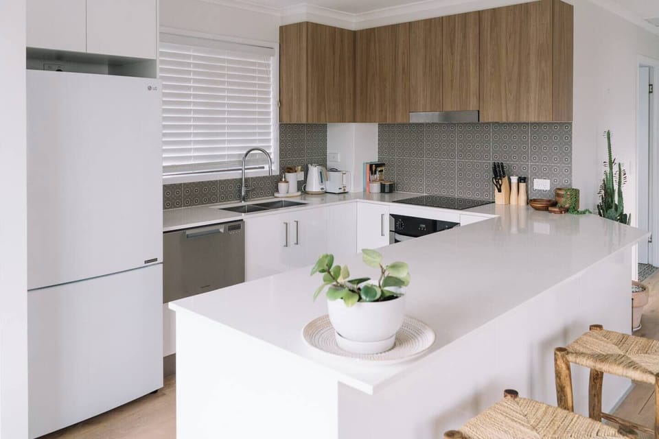 The modern, renovated kitchen has a washing machine hidden in one of the cupboards creating at-home laundry convenience.