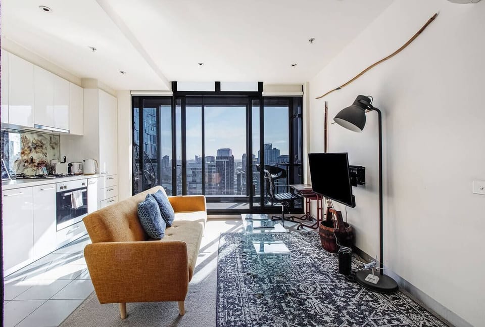 A plush sofa invites cosy nights at home, perfect for watching TV. The room is filled with natural light, leading to the balcony.