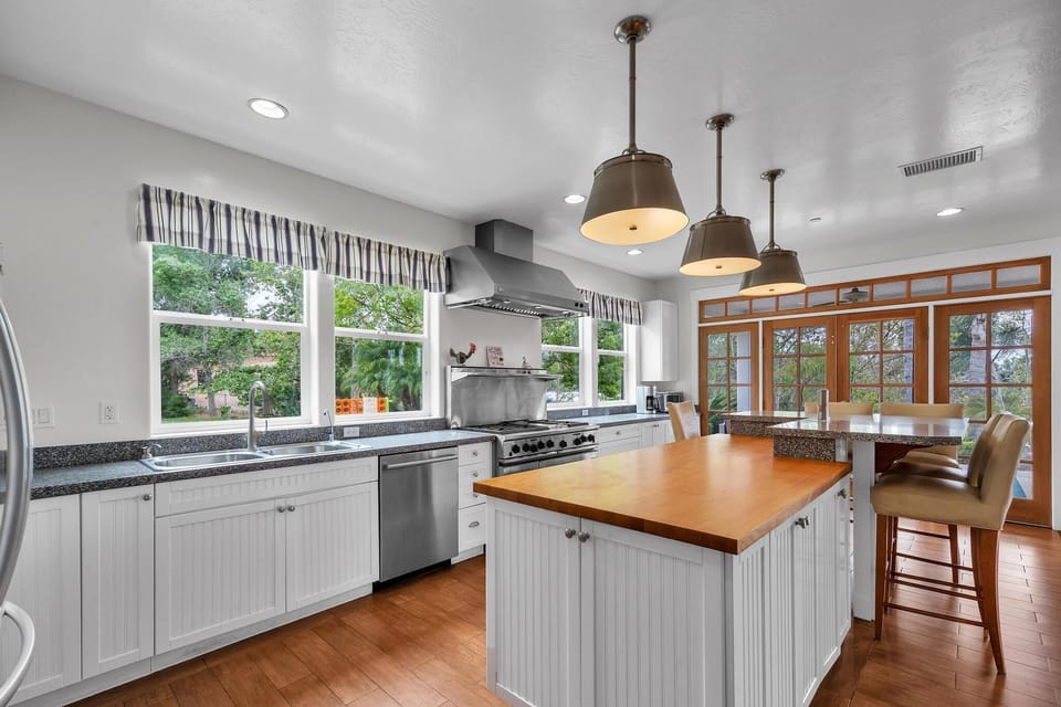 Cook and dine in the kitchen with barstools, stainless steel appliances, two ovens, and a large fridge. Bright, airy space perfect for family meals and entertaining.