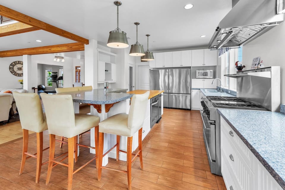 Cook and dine in the kitchen with barstools, stainless steel appliances, two ovens, and a large fridge. Bright, airy space perfect for family meals and entertaining.