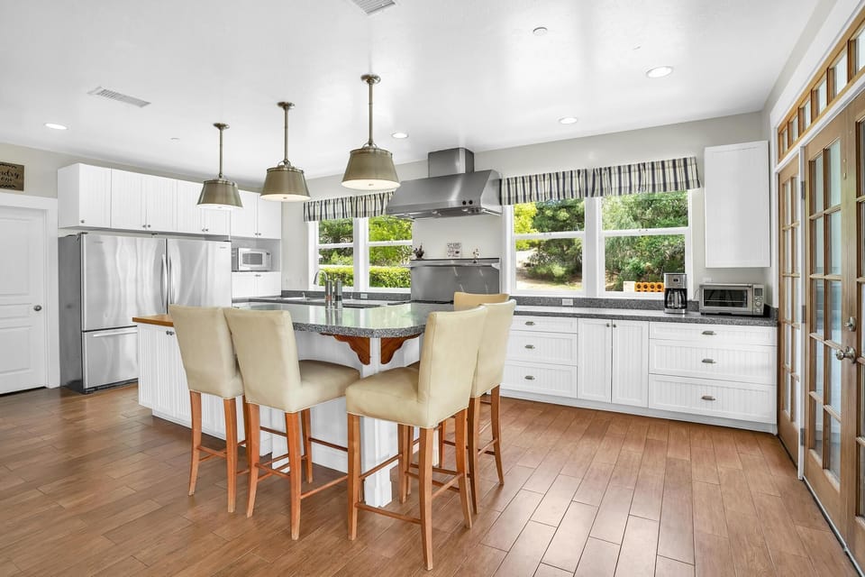 Cook and dine in the kitchen with barstools, stainless steel appliances, two ovens, and a large fridge. Bright, airy space perfect for family meals and entertaining.
