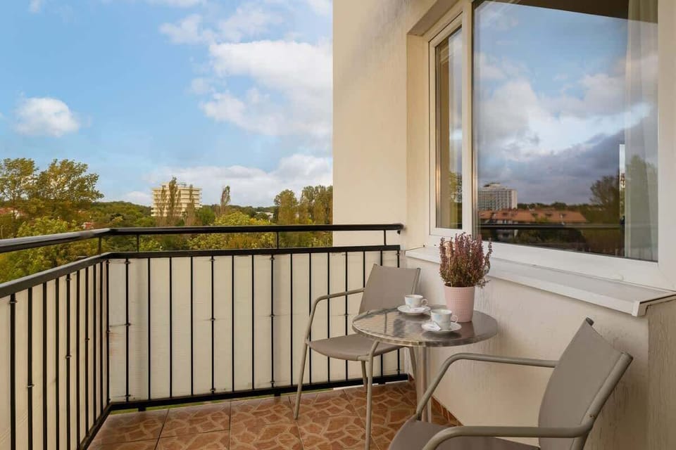 A balcony with a scenic view of the surrounding area, decorated with small plants and comfortable seating.
