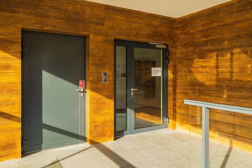 The entrance to the building, featuring a wood-paneled facade and large glass doors for a welcoming appearance.
