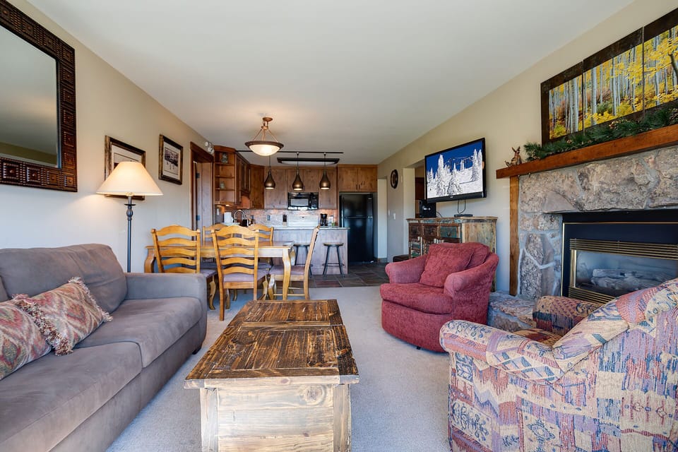 Settle into this cozy living room where you'll find comfortable seating by a stone fireplace, with a full kitchen ready for your mountain getaway.