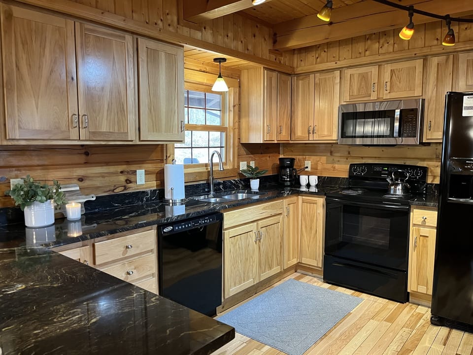 Fully equipped kitchen with modern appliances, a spacious island with bar seating, and charming wood finishes—perfect for preparing meals and enjoying casual dining or drinks.