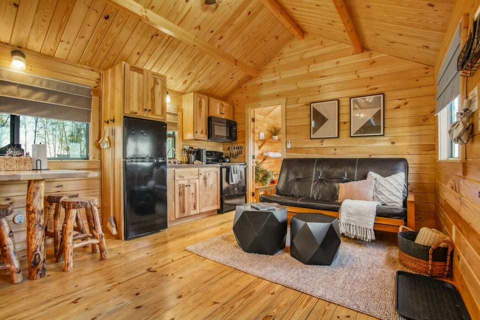 Cabin interior with warm wood finishes, full kitchen, and comfy lounge area