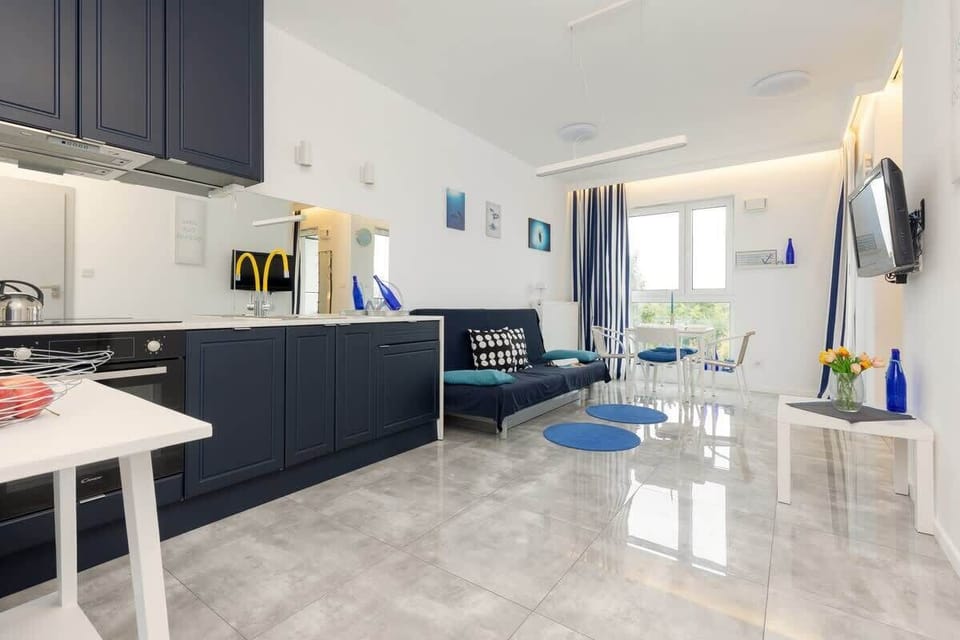 A dining area by the window, featuring a white table, blue chairs, and natural light enhancing the space.
