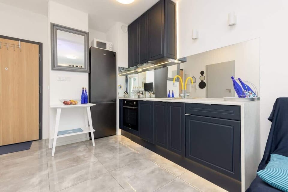 A modern kitchen with dark cabinets, light countertops, and a sleek design seamlessly integrated with the living area.
