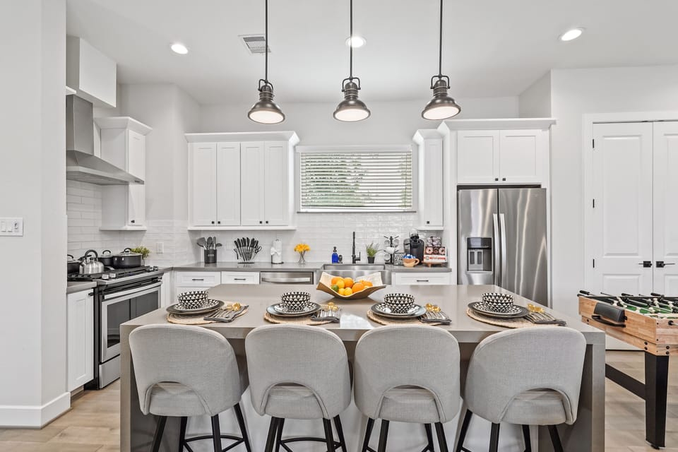 Bright modern kitchen with island seating, pendant lights, and stainless fridge