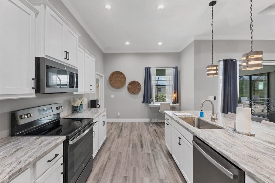 Immaculate kitchen with granite counter tops and black stainless appliances 