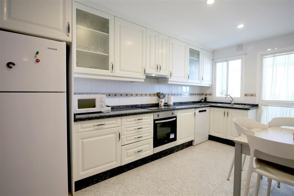 Kitchen with dining table for three guests and laundry room to the rear