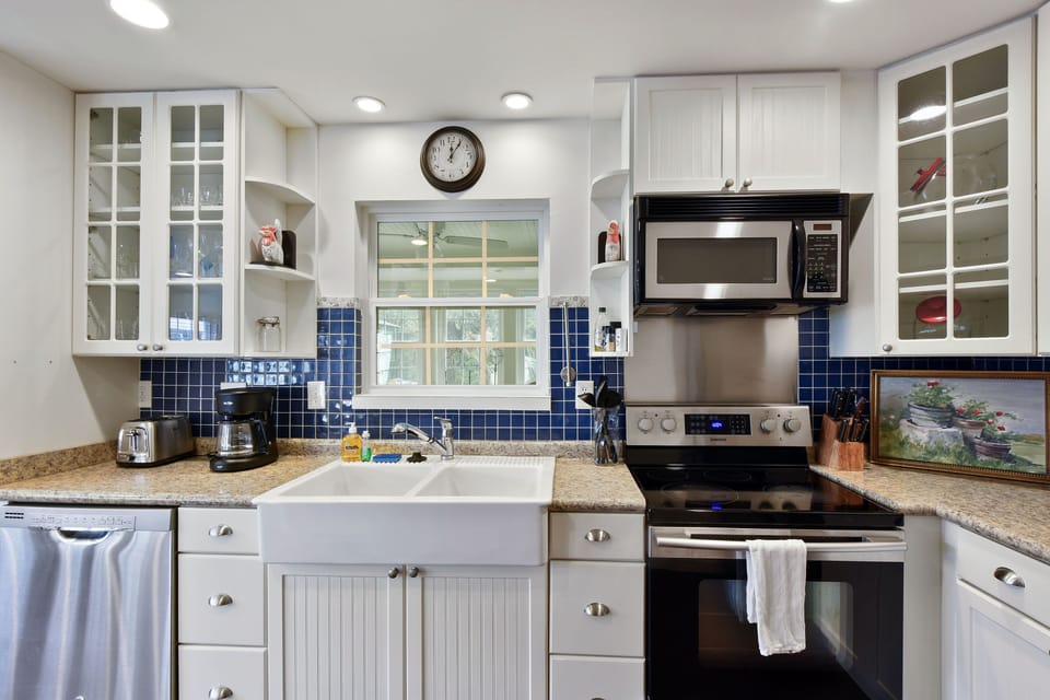 Kitchen with Blue Tile Backsplash - Stainless appliances, white cabinets, blue tile backsplash, coffee maker, and stocked counter space.