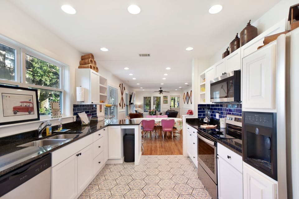 Galley Kitchen With Navy Tile And Island - Full kitchen angle with patterned floor tile, stainless appliances, navy backsplash, and island seating.