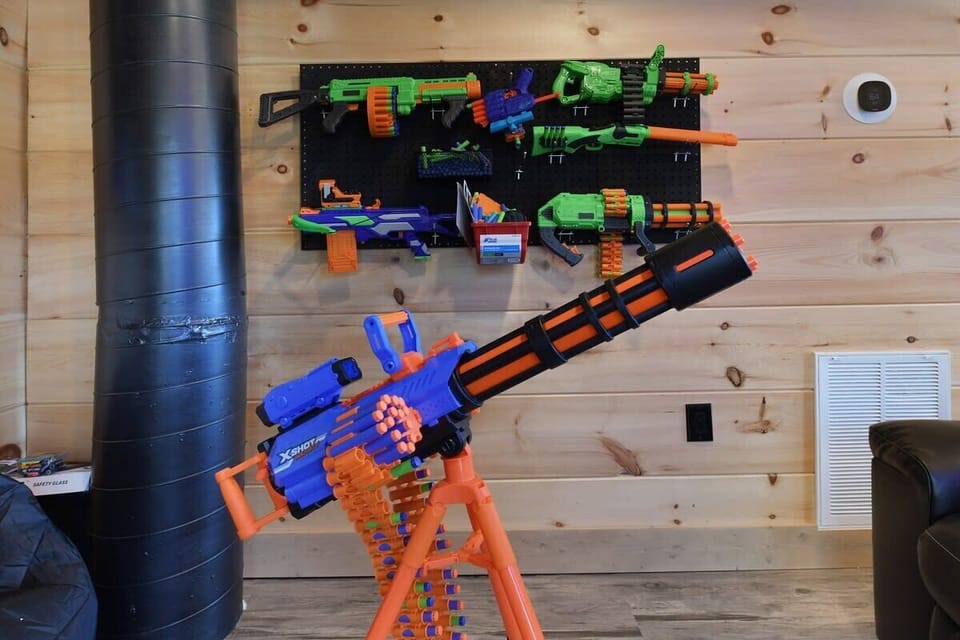 A collection of colorful toy dart blasters displayed on a wooden wall in a playful setting.