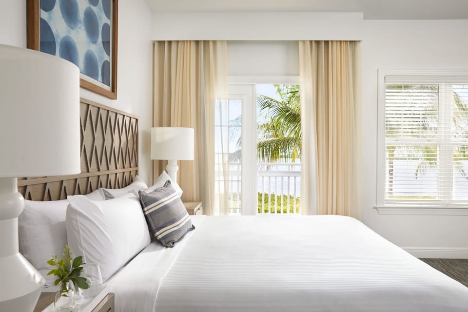 Sink into crisp linens beside soft drapes and airy windows.