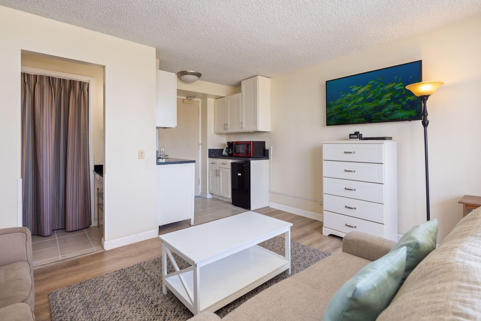 Your bright, open living space flows seamlessly into a convenient kitchenette, perfectly designed for relaxing after a day of exploring. Comfortable seating and vibrant art await your arrival.