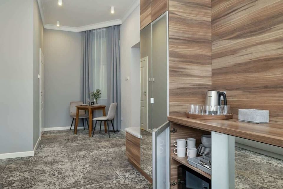 A wider shot of the bedroom, revealing the bed, part of the grey sofa, and a desk next to a wooden divider.
