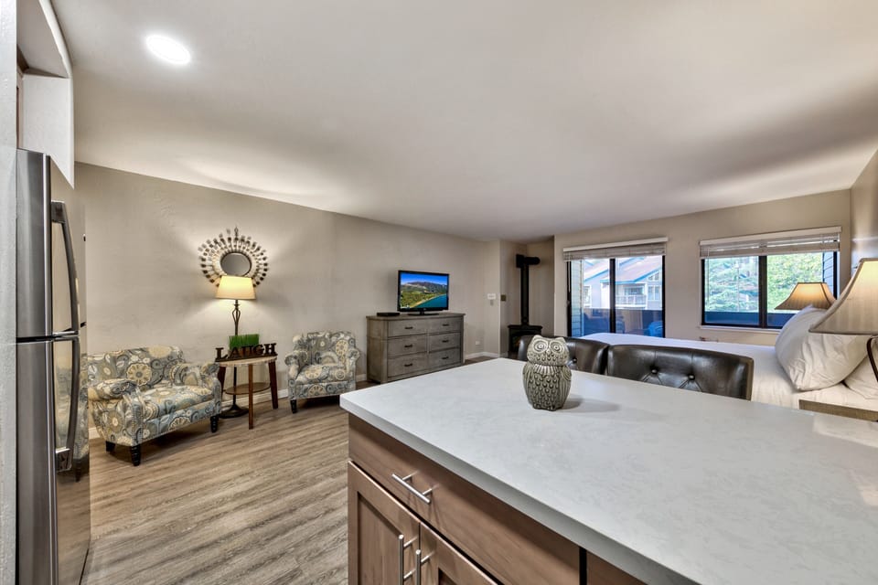 Relax in your stylish open living space with modern kitchen, cozy seating, and mountain views through expansive windows.