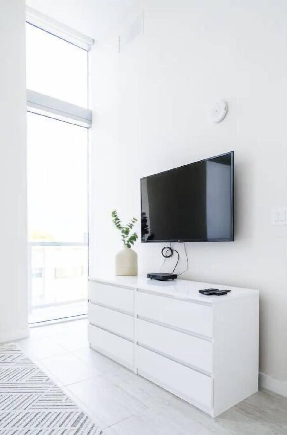 Wall-mounted TV above a sleek dresser.